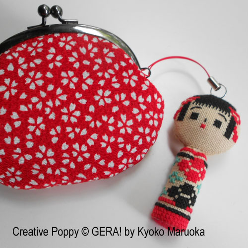 cross stitch kokeshi doll used as a charm on a bag 